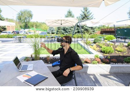 Businessman Working With Papers And Laptop, Enjoying Virtual Reality Glasses In Open Air . Conceptof