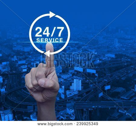 Hand Pressing Button 24 Hours Service Icon Over Modern City Tower, Street And Expressway, Full Time 