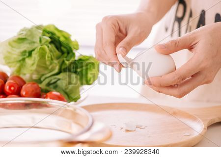 Female Hands Is Shelling Chicken Eggs. The Woman Prepares Breakfast At Home. Boiled Chicken Eggs In
