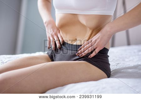 Too Slim. Waist Of A Underweight Young Woman While Sitting On The Bed