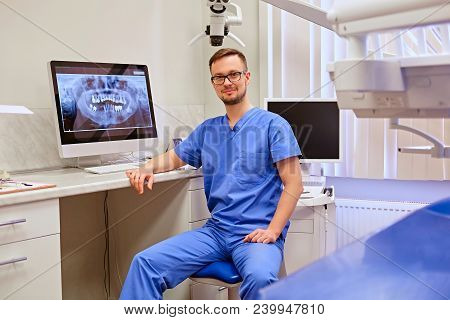 Male Dentist Looking At Teeth X-ray On The Computer In A Dentist Office.