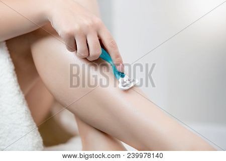 Closeup Image Of Young Woman Removing Hair From Legs With Razor