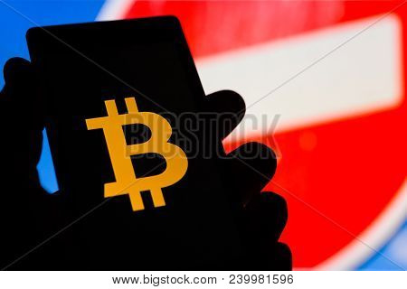 Smartphone In Hand With Bitcoin Cryptocurrency Logo. Prohibiting Red Sign On Background. Banned Mone