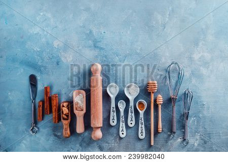 Measuring Spoons, Wooden Scoops, Whisks, Rolling Pin, Honey Spoons, Sugar And Cinnamon On A Blue Con