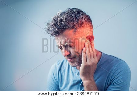 Male Having Ear Pain Touching His Painful Head Isolated On Gray Background