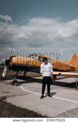 A Man Standing On The Background Of A Small Single Engine Plane.