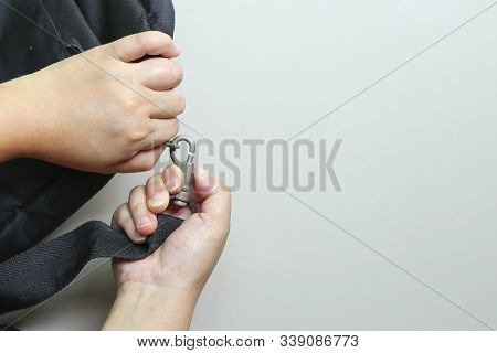The Hand That Is Releasing The Sash From The Bag. Remove The Sash From The Bag.