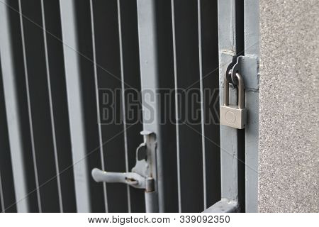 Silver Padlock Locking The Gray Iron Door. Silver Padlock Locking Steel Doors Safely.