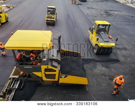 Road-building Machinery And Workers Conduct Asphalt Work In The Parking Lot At The Shopping Center U