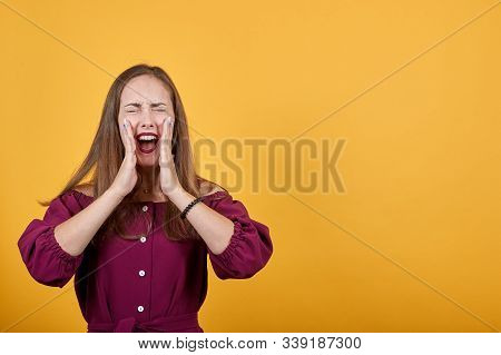 Young Woman With Burgundy Bluse Over Isolated Orange Background Shouting With Mouth Wide Open. Girl 