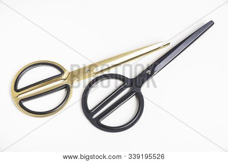 Two Pairs Of Retro Or Vintage Style Scissors In Black And Gold Set On A Plain White Background.