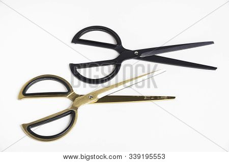 Two Pairs Of Retro Or Vintage Style Scissors In Black And Gold Set On A Plain White Background.