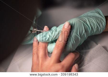 A Manicure Hand With A Nail Lies On A Manicure Hand In Blue Hygienic Gloves.hands On The Manicure Of