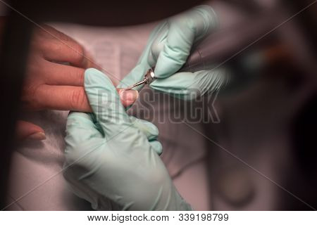 A Manicure Hand With A Nail Lies On A Manicure Hand In Blue Hygienic Gloves.hands On The Manicure Of