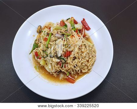 Thai Food Style, Top View Of Instant Noodle Spicy Salad With Sausage In White Plate Isolated On Wood