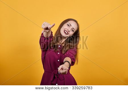 Young Lady In Burgundy Bluse With Bow Pointing Finger At You And Smiling Over Isolated Orange Backgr