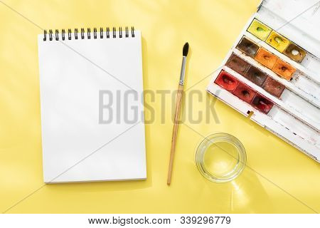 White Clean Notepad On Black Spring, Squirrel Brush, Jar Of Still Water And Watercolor Paints On Bri