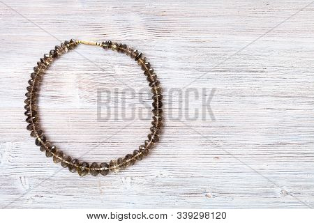 Top View Of Faceted Smoky Quartz Necklace On Gray Wooden Board With Copyspace