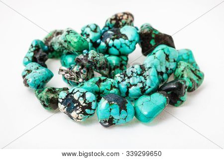 Tangled String Of Beads From Natural Tumbled Dyed Howlite Gemstone On White Paper Background