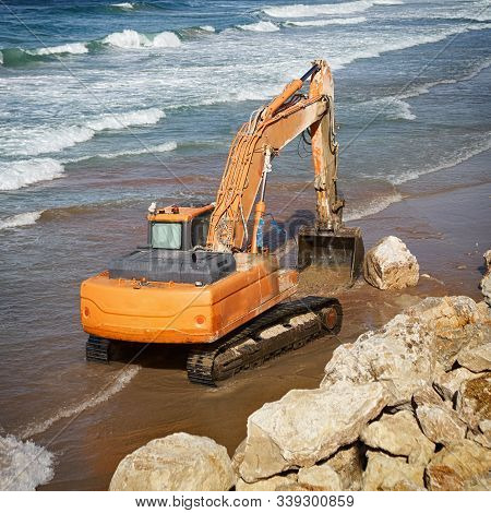 Orange Excavator Working On The Beach In Warm Weather