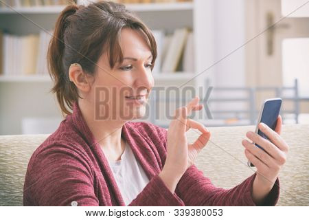 Deaf woman wearing hearing aid and using smartphone
