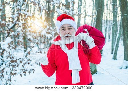 Santa Claus With Bag Walking In Winter. Thanksgiving Day And Christmas. Santa Carrying Sack Of Gifts