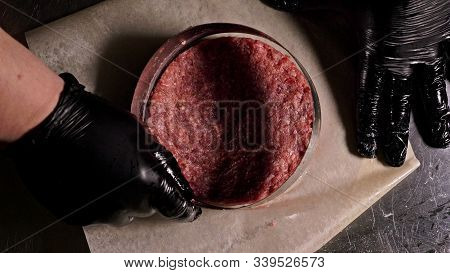Cook Makes Meat Medallions For Burgers. Chef In Black Food Gloves Makes Cutlet. Cutlets Are Leveled 