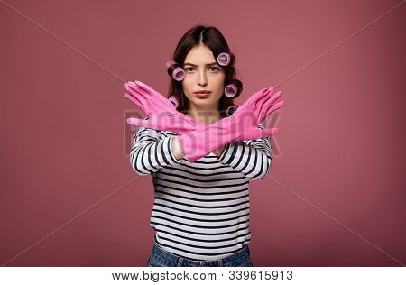 Sad Young Beautiful Woman In A Striped Sweater And Pink Curlers Posing In Gloves For Washing Dishes.