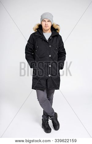 Fell Length Portrait Of Young Handsome Man Posing In Warm Winter Clothes Over Gray Background