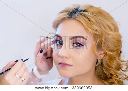 Make-up Artist Doing Makeup For A Beautiful Young Red-haired Girl In A Beauty Salon, A Concept Of Pr