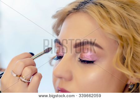 Make-up Artist Doing Makeup For A Beautiful Young Red-haired Girl In A Beauty Salon, A Concept Of Pr