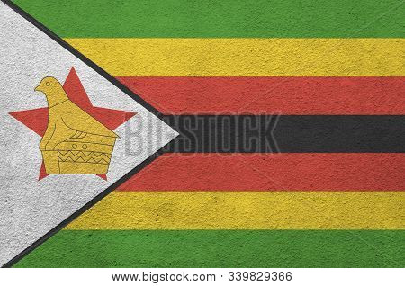 Zimbabwe Flag Depicted In Bright Paint Colors On Old Relief Plastering Wall. Textured Banner On Roug
