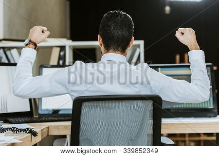 Back View Of Bi-racial Trader Showing Yes Gesture And Sitting At Table