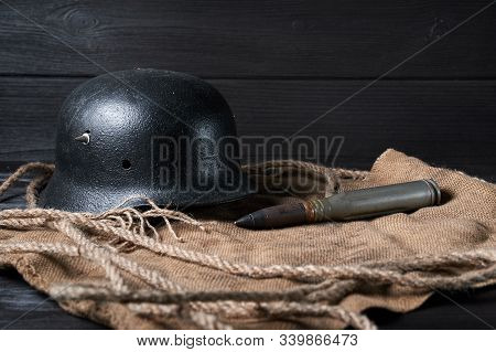 Still Life German Helmet And Heavy Cartridge On A Black Background And Burlap