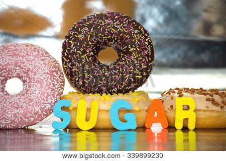 Group Of Delicious Colorful Glazed Donuts Near Colorful Background With The Word Sugar