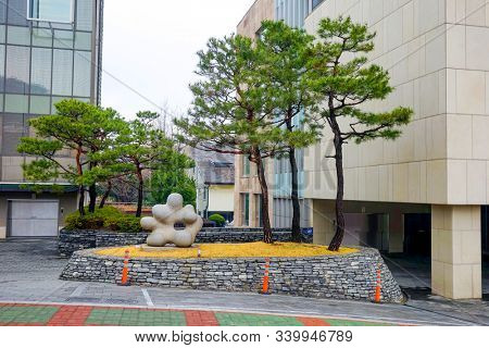 Seoul, March - 2019: Small architectural forms. Stone abstraction and green pine trees. Office buildings.