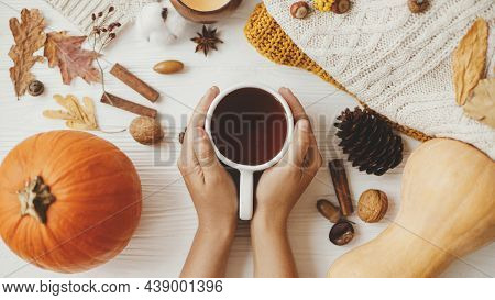 Hello Autumn, Cozy Slow Living. Hands Holding Warm Cup Of Tea On Background Of Autumn Leaves, Pumpki