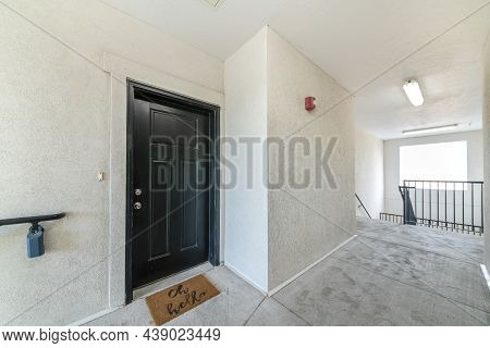 Black Front Door Of An Apartment With Statement Doormat