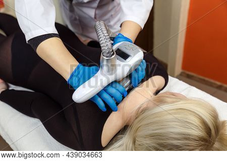 Close-up Of A Therapist Beautician Makes A Lpg Massage To A Young Woman In A Dark Transparent Suit. 