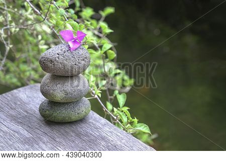 Stones Stacked On Top Of Each Other, Next To Nature Flowers And Pond.