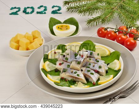 Herring Fish. Salted Herring Fillet With Lemon On Spinach Leaves On A White Background. Cherry Tomat