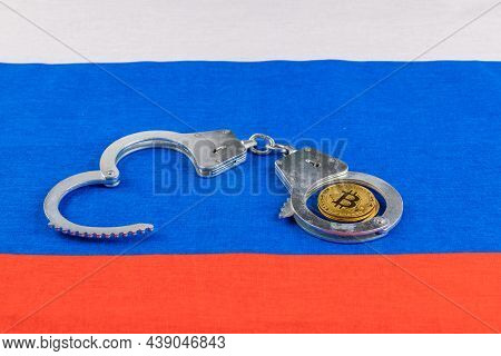 Roll Of Russian Paper Rubles Currency And Bitcoin Shiner Chained With Handcuffs On Russian Flag Back