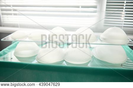 Medical Sample Of Silicone Implants Of Various Shapes And Sizes For Breast Augmentation On Glass Sur