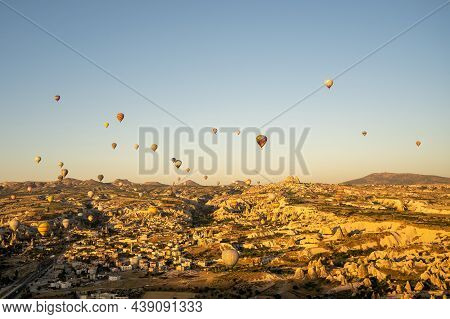 Sunrise View Of Unusual Cityscape. Colorful Hot Air Balloons Fly In Blue Sky Over Amazing Valleys An
