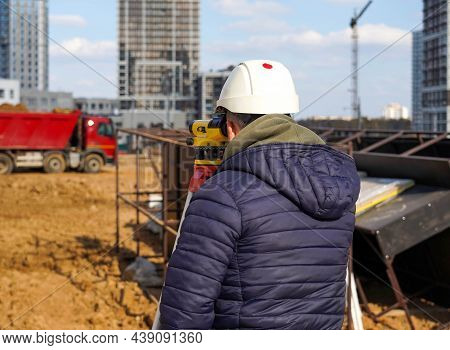 Photo Of A Construction Worker In A White Helmet Who Looks Into The Level At The Construction Site O