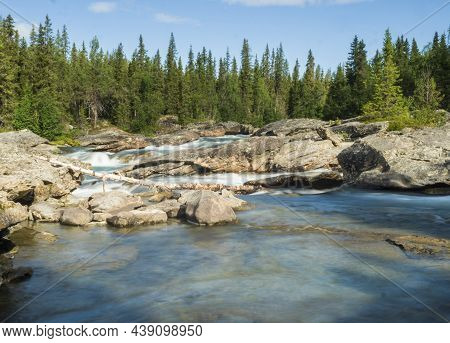 Beautiful Landscape With Long Exposure Water Stream And Cascade Of River Kamajokk, Boulders And Spru