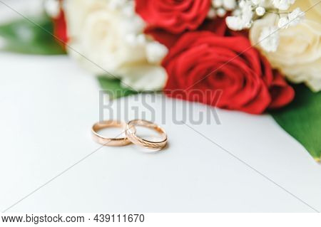 Gold Wedding Rings And Flowers Bouquet In White Red Colors Lying On White Background. Declaration Of