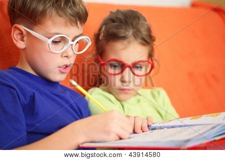 Ragazza e ragazzo intensamente facendo i compiti, messa a fuoco sui vetri cerniera.
