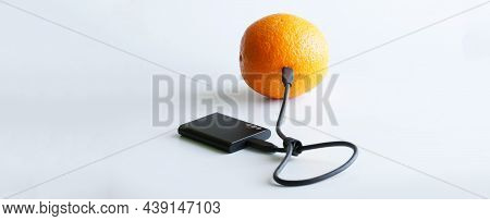 Black External Ssd Is Wired To A Fresh Orange. Concept Of Green Technologies, Storage And Transmissi