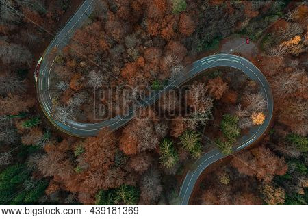 Eycatching Drone View At A S-curve In The Fall Season With Light Trails Of Driving Cars At The Bendi